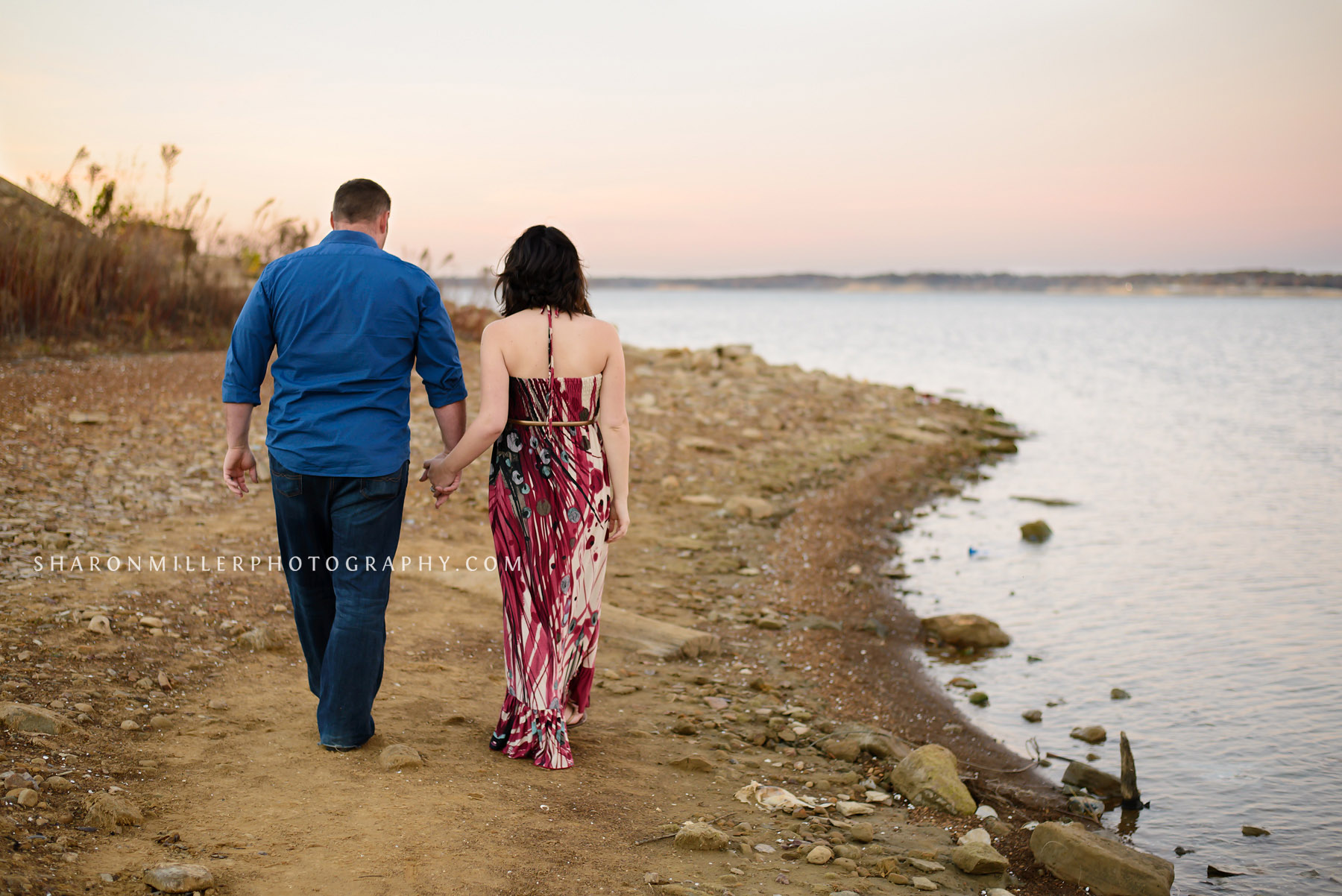 maternity couple walking into sunset at Grapevine Lake