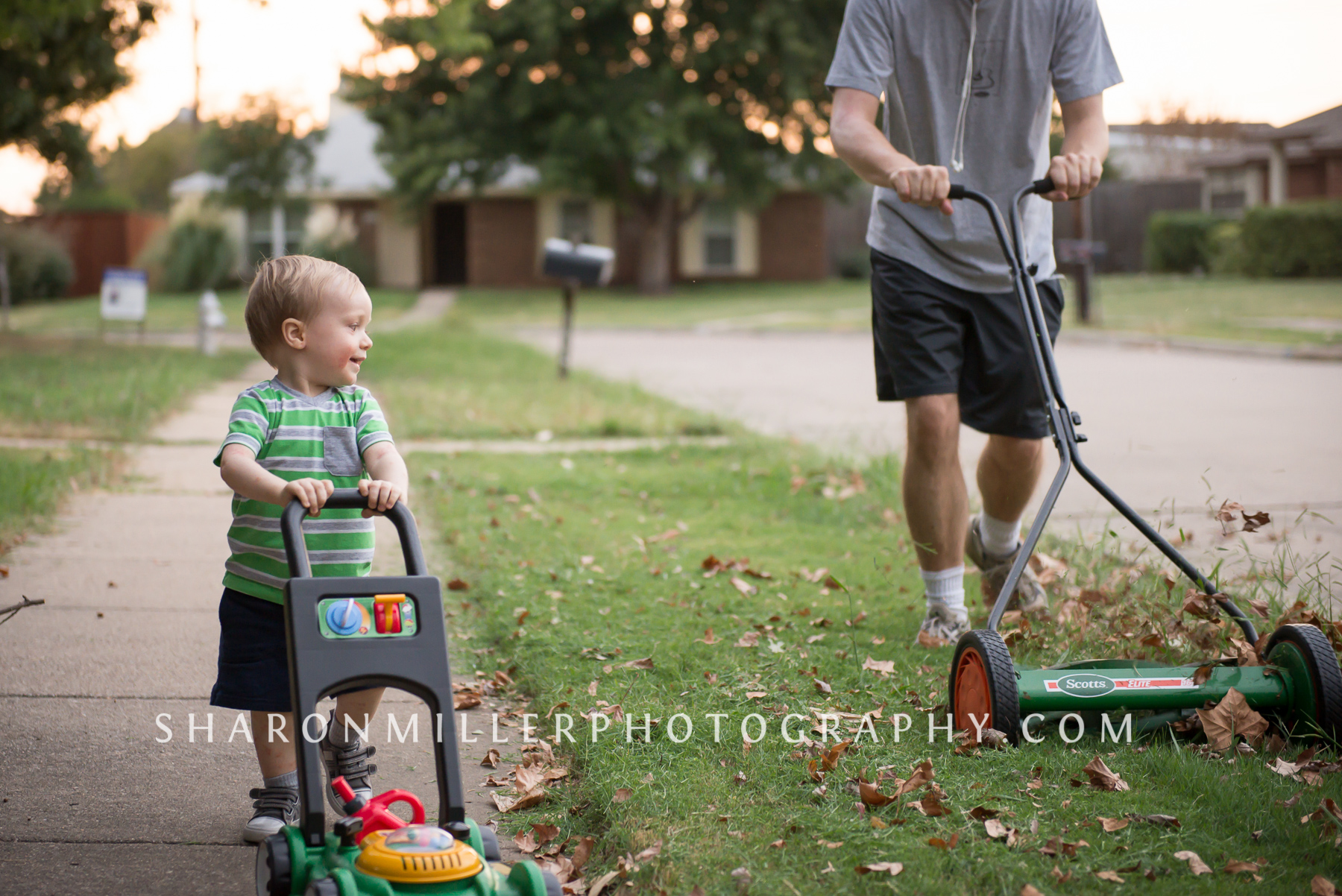 storytelling photography showing a young boy pushing toy lawn mower next to daddy's reel lawn mower