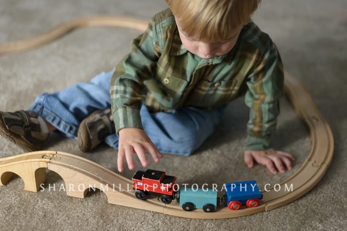 little boy playing with wooden train set and track