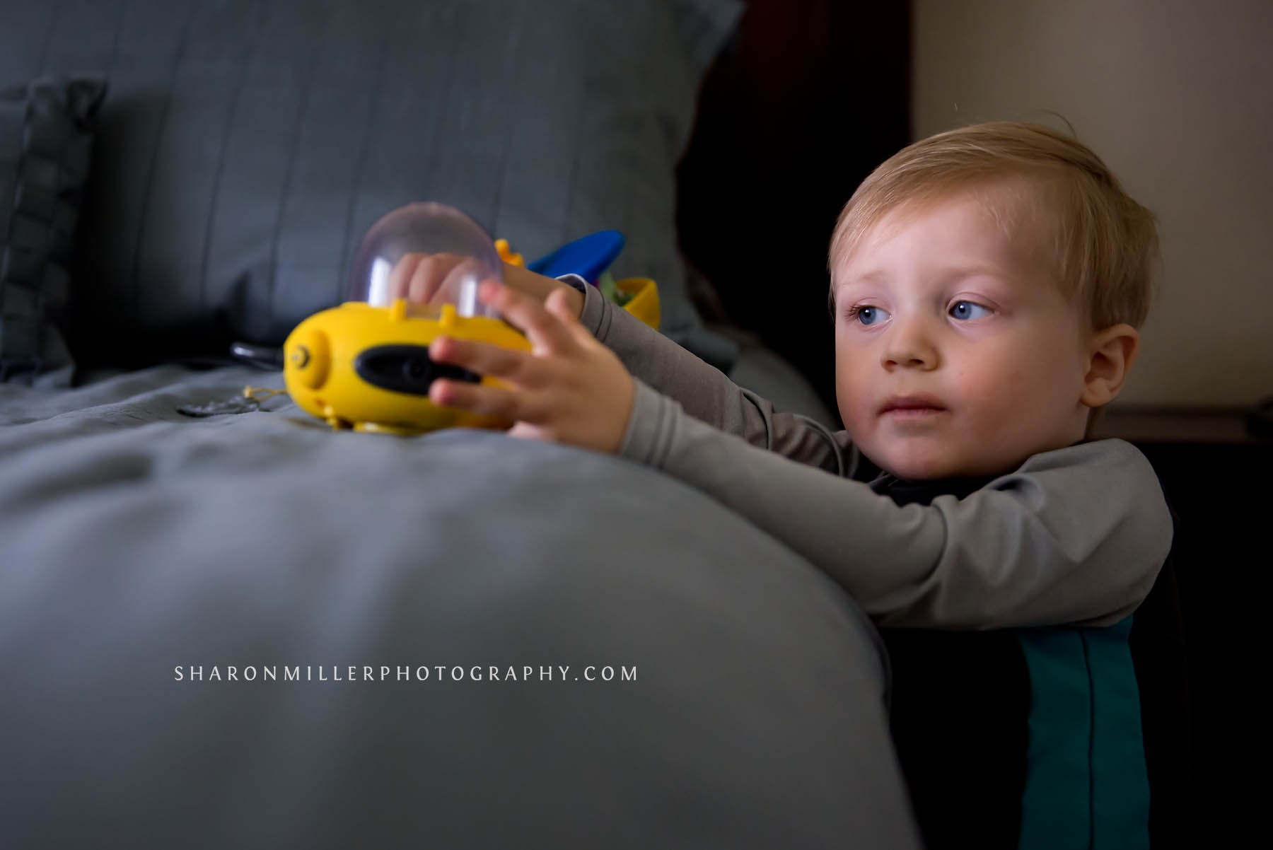 boy playing with Octonauts toys on the edge of his parents' bed