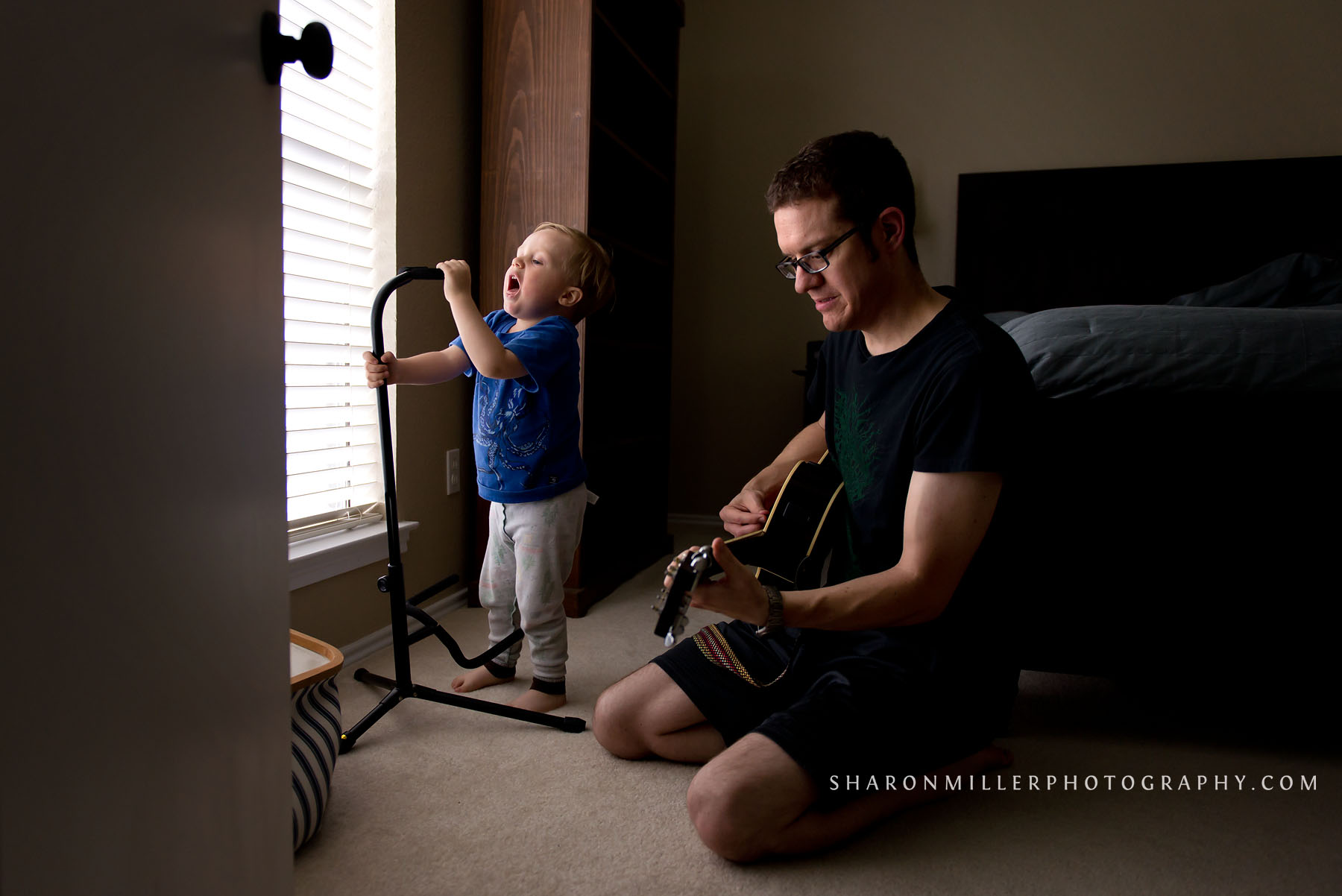 boy singing into a guitar stand microphone with his daddy accompanying him on guitar