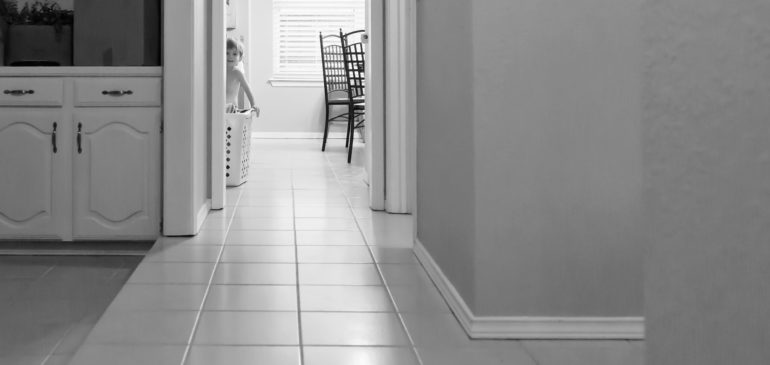 documentary photo of boy pushing laundry basket through kitchen